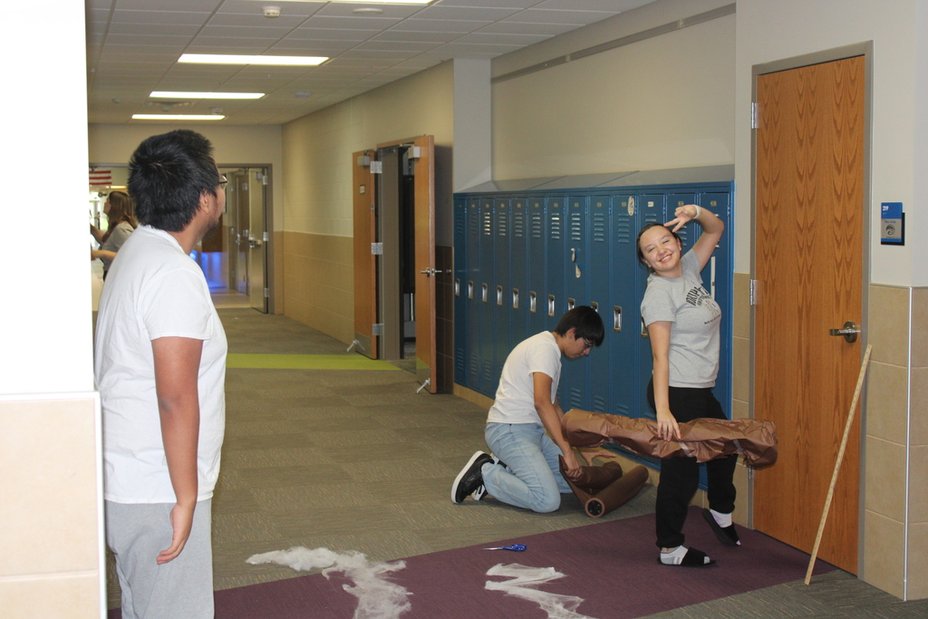 three juniors hanging things in their hallway