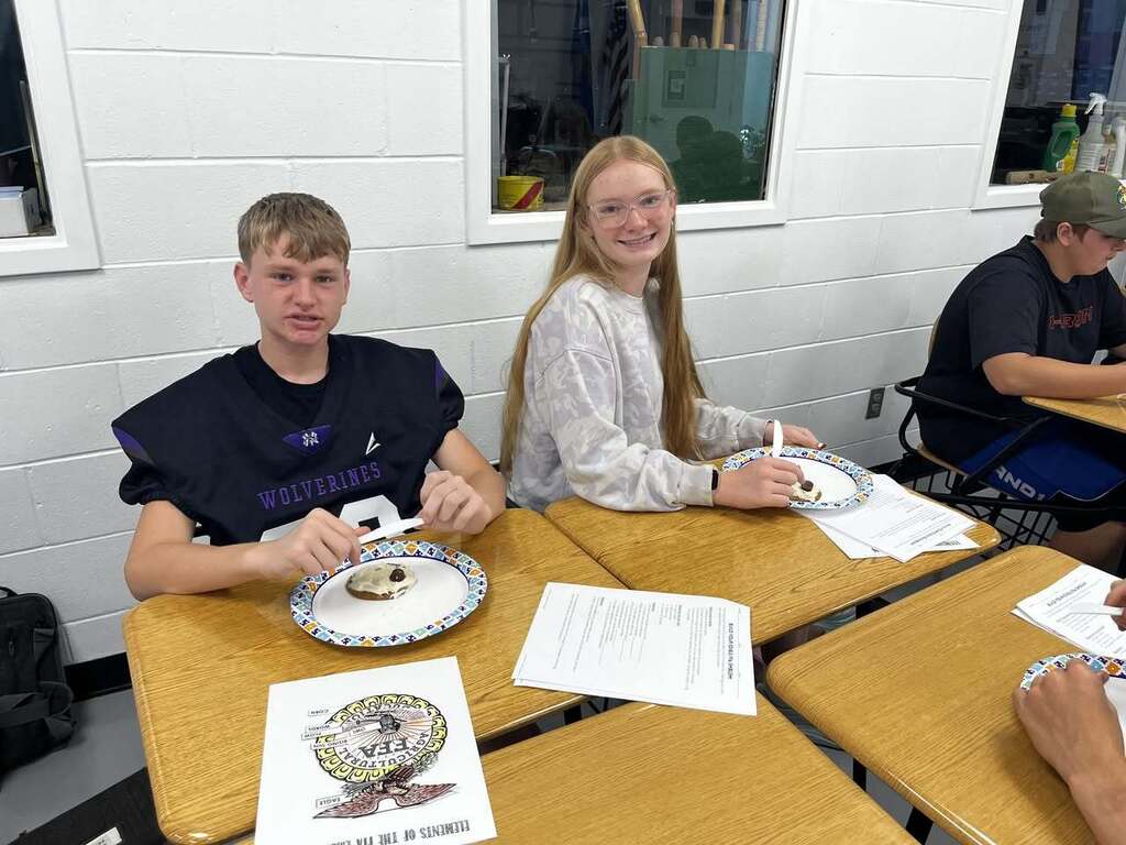 Students at table eating cookies