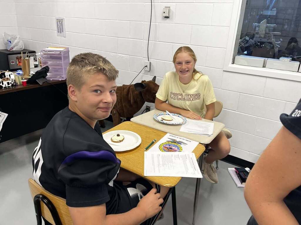 Two students at table looking back at camera