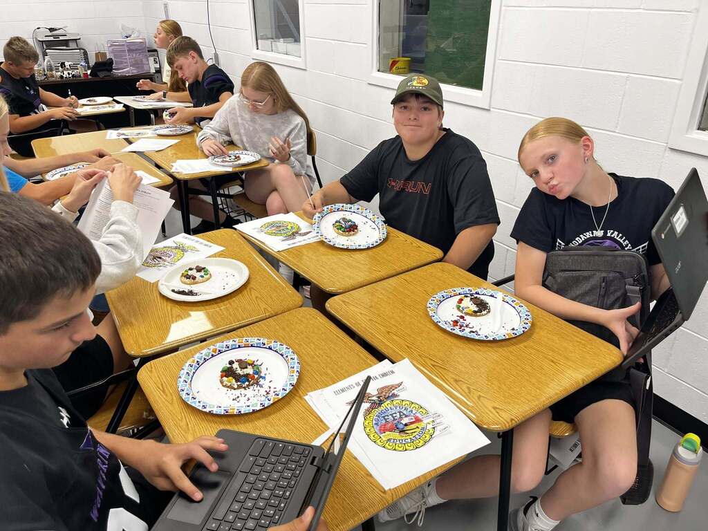 Students at desks eating their cookies taking pictures of them on their Chromebooks