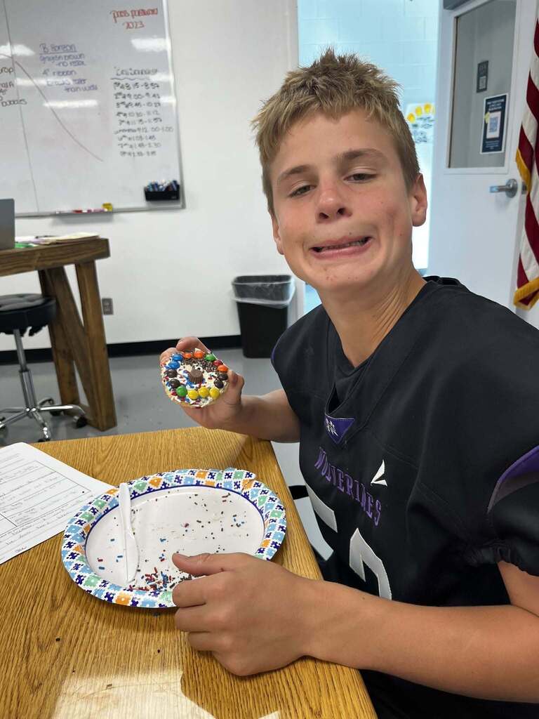 One student eating a cookie making a funny face at the camera