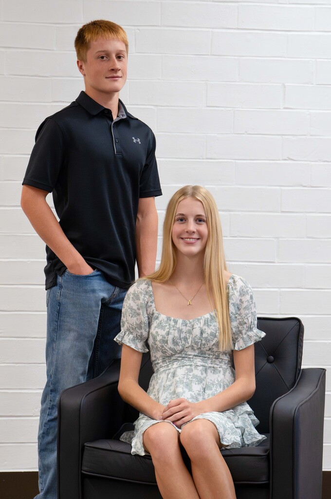Two homecoming candidates posing with one standing behind the one sitting