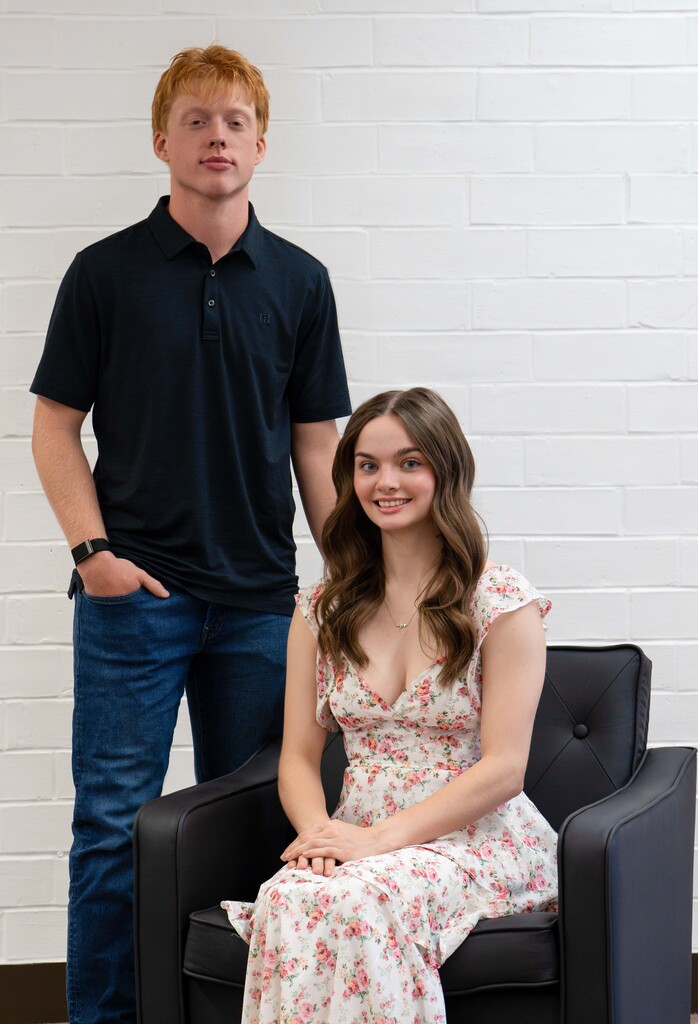 Two homecoming candidates posing with one standing behind the one sitting