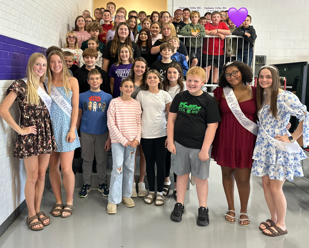Homecoming Court members pose with a large group of middle school students on the cafeteria steps.