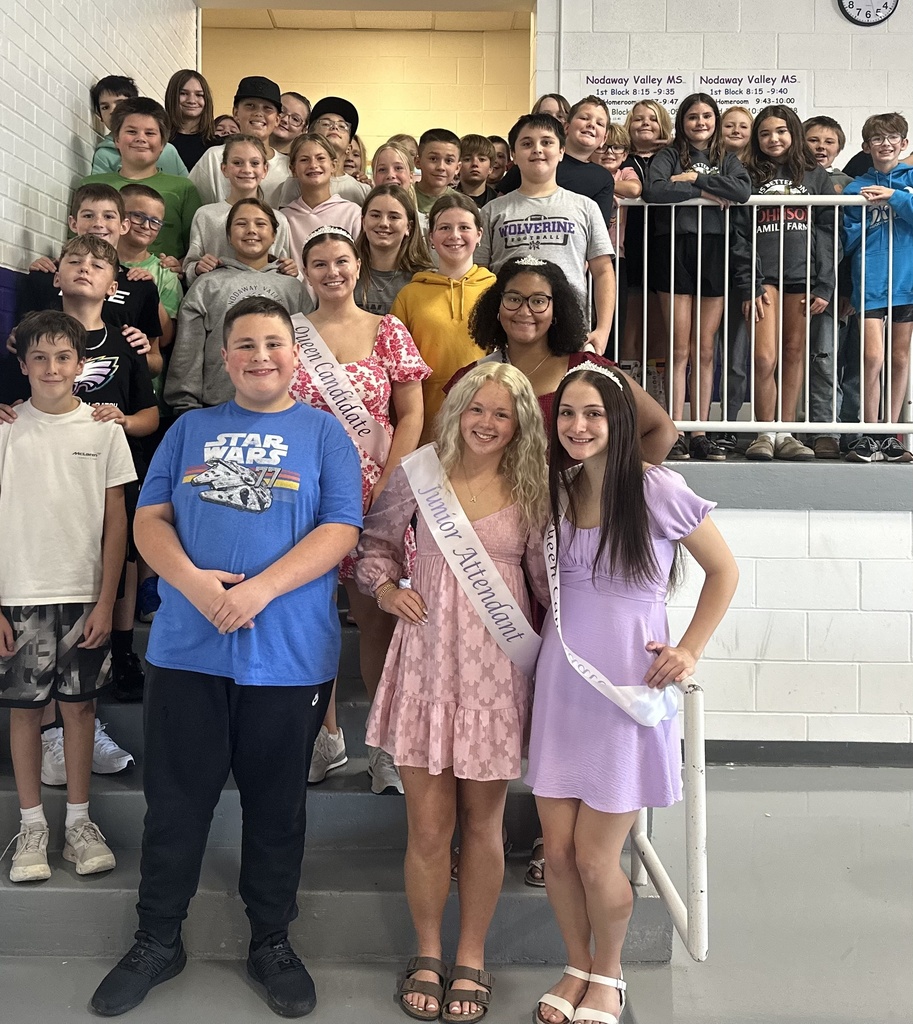 Homecoming Court members and a large group of middle school students pose together on the cafeteria steps.
