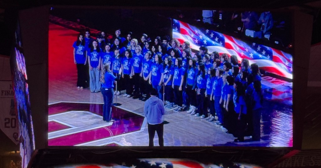 Photos of Whittier Choir singing at the OU Women's Basketball Game.