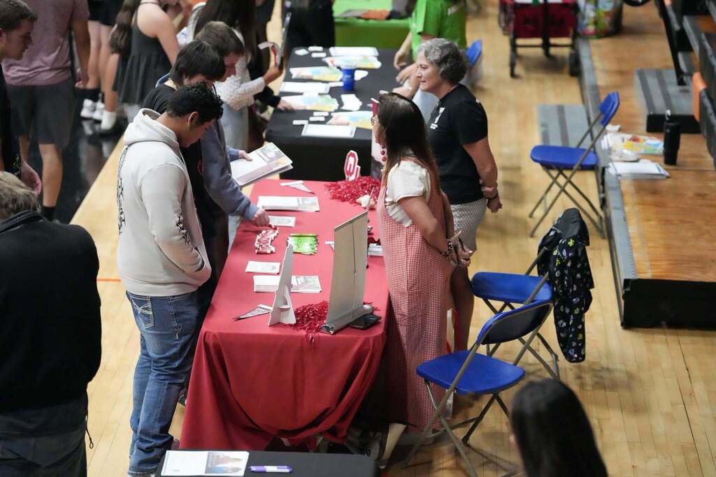 A group of people around a table with a red cloth, examining information on it.