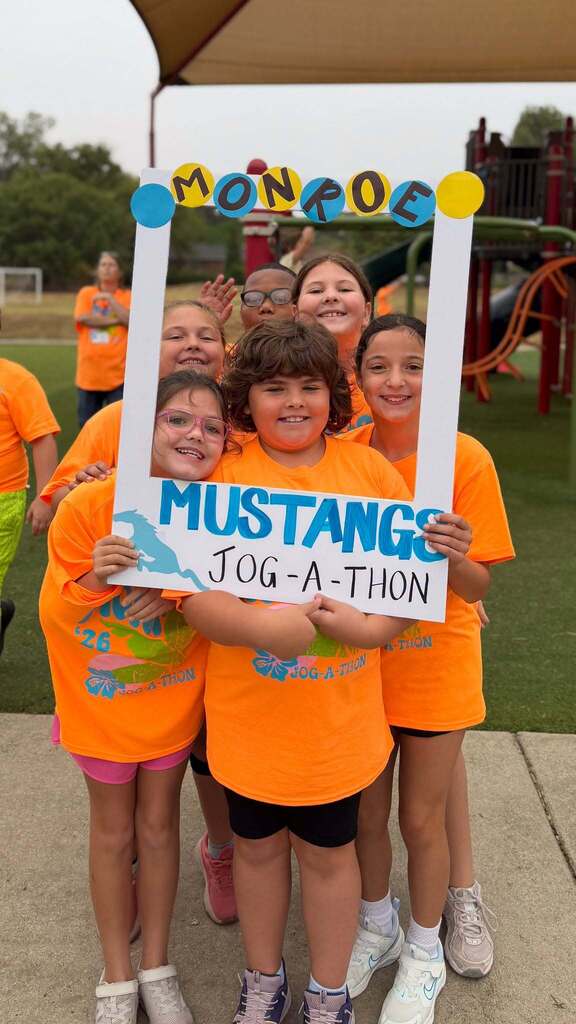 Five children in orange shirts pose with a sign reading "MONPOE MUSTANGS JOG-A-THON." Behind them is a playground.