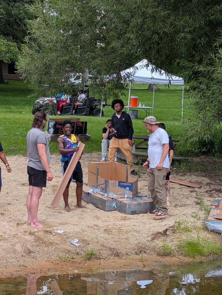 learner and staff at pond with cardboard boat