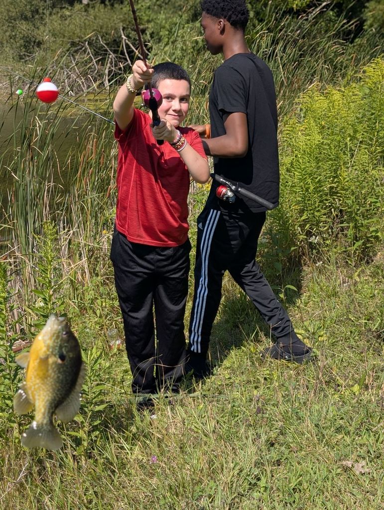 young male learner holding a fishing pole with fish