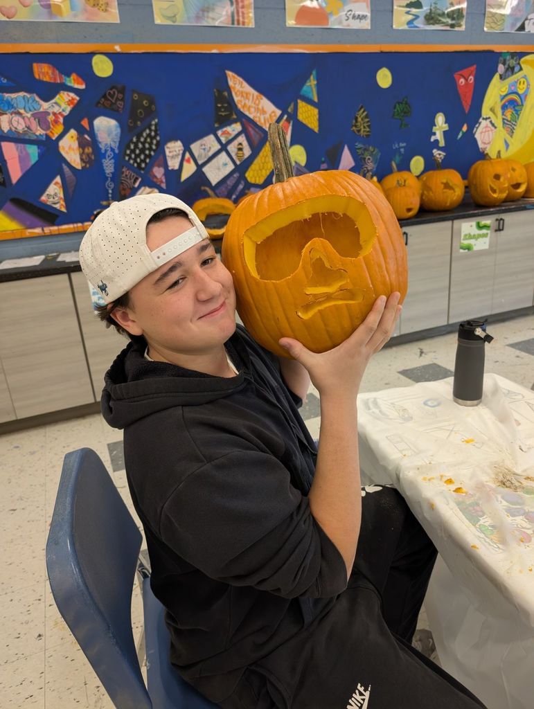 learner showing off carved pumpkin