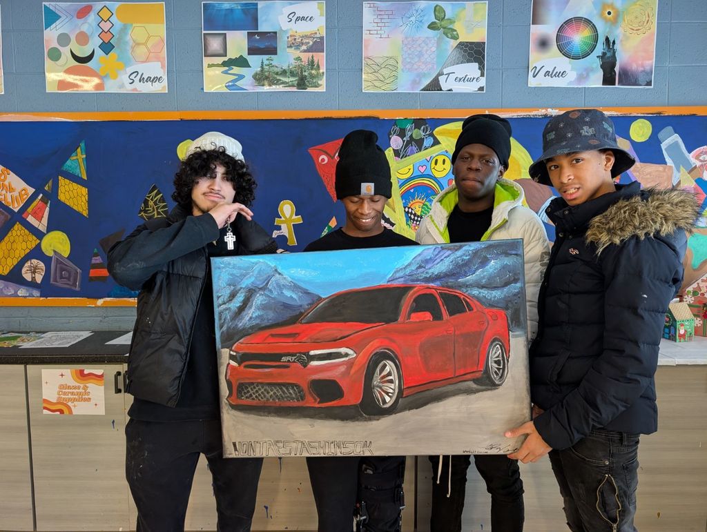 Learners holding a painting they created. 