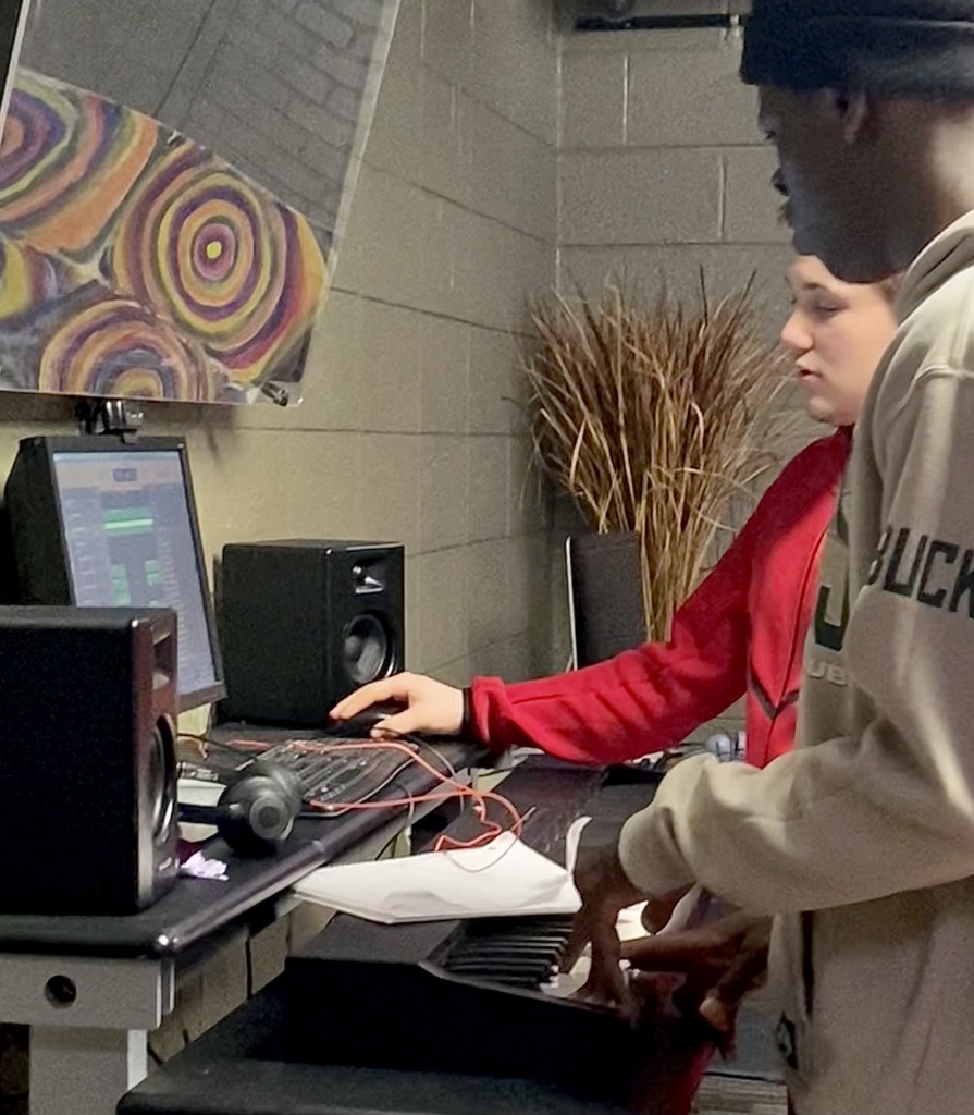 two male learners working together in a studio to make music. 