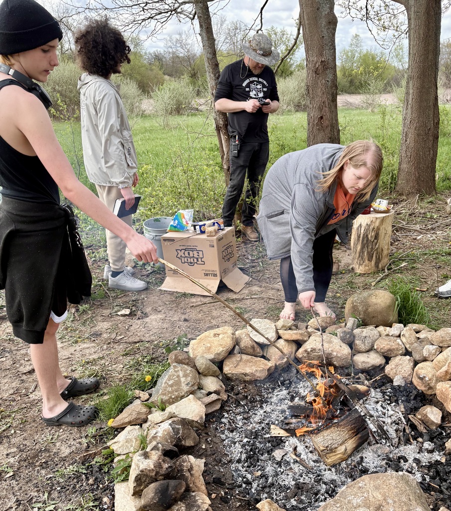 Staff and learner around a fire