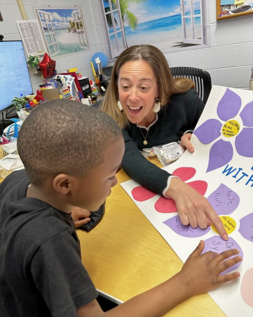 Teacher enthusiastically helping a student with a colorful educational activity in a classroom