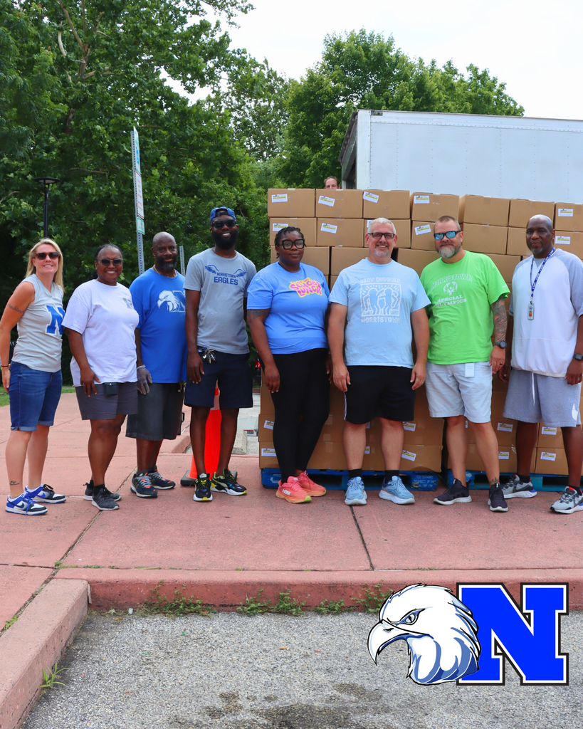 NASD Staff members pose for photo in front of meal distribution boxes