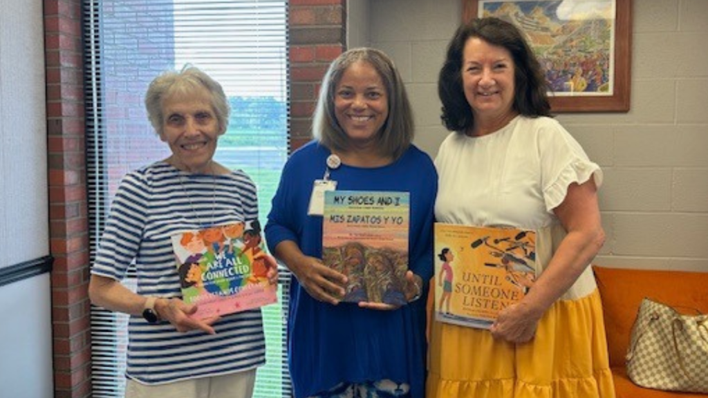 Cabrini representatives and NASD Chief Academic Officer pose for photo holding some of the donated books