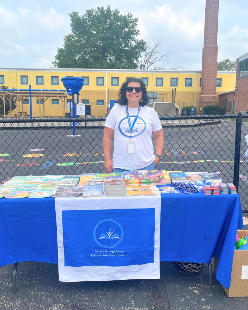 NASD Staff members stands behind table with free books.