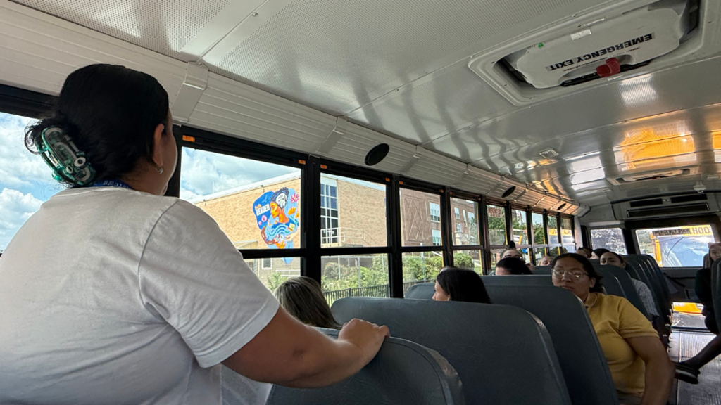 Bus Tour Guide speaking to new teachers on the bus while looking out the window.