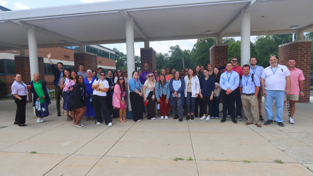 New Teachers and Bus Tour Guides pose for large group photo before getting on the buses.
