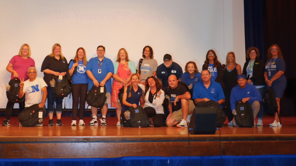 Staff members with 25 years of service to NASD pose for group photo on stage.