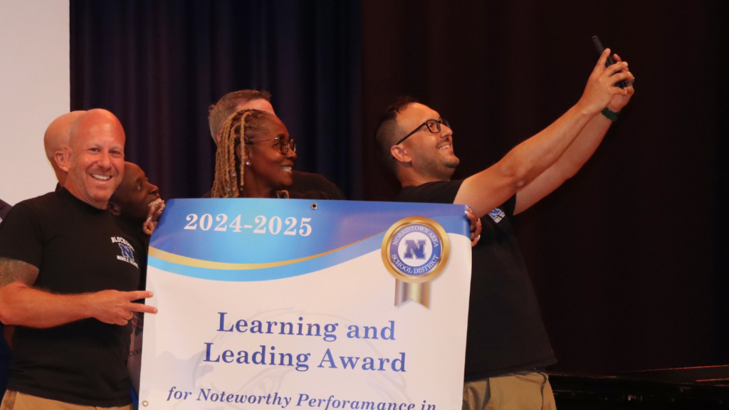 Blockson team taking a selfie on stage holding their learning and leading award.