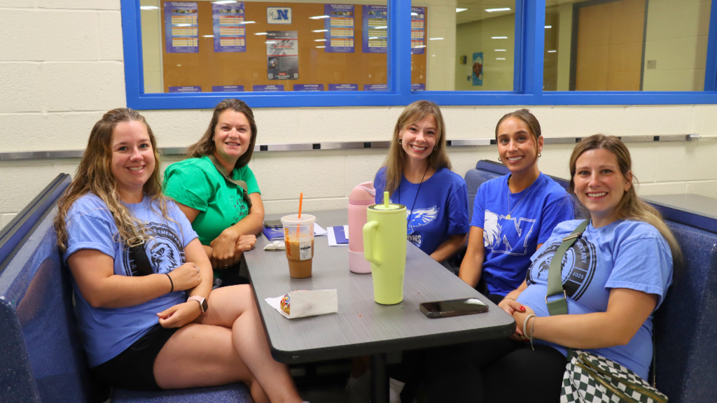 Teachers sitting at table in NAHS cafeteria before the opening ceremony begins.