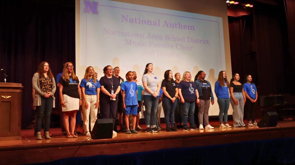 NASD Faculty Choir and guests singing on stage.