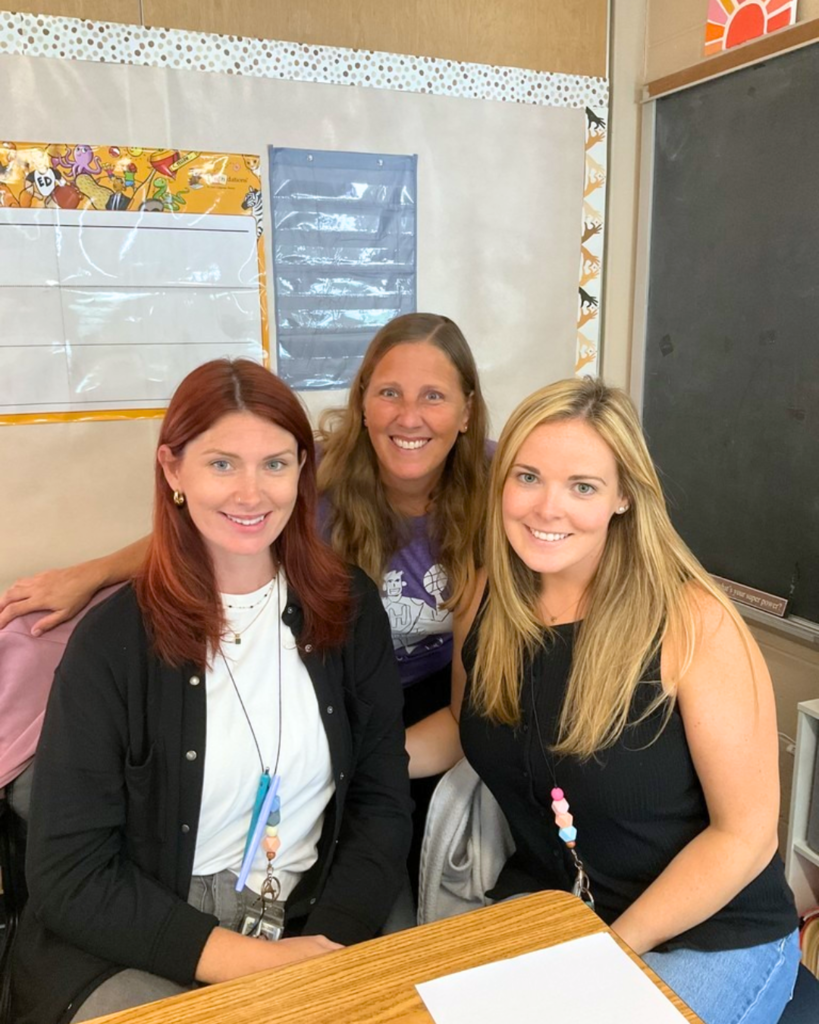 Three staff members pose for photo in a classroom.