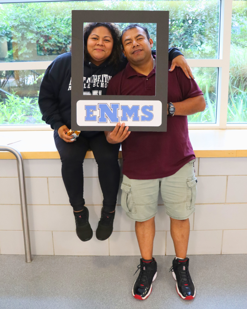 Two adults holding a poster photo frame smiles for a photo.