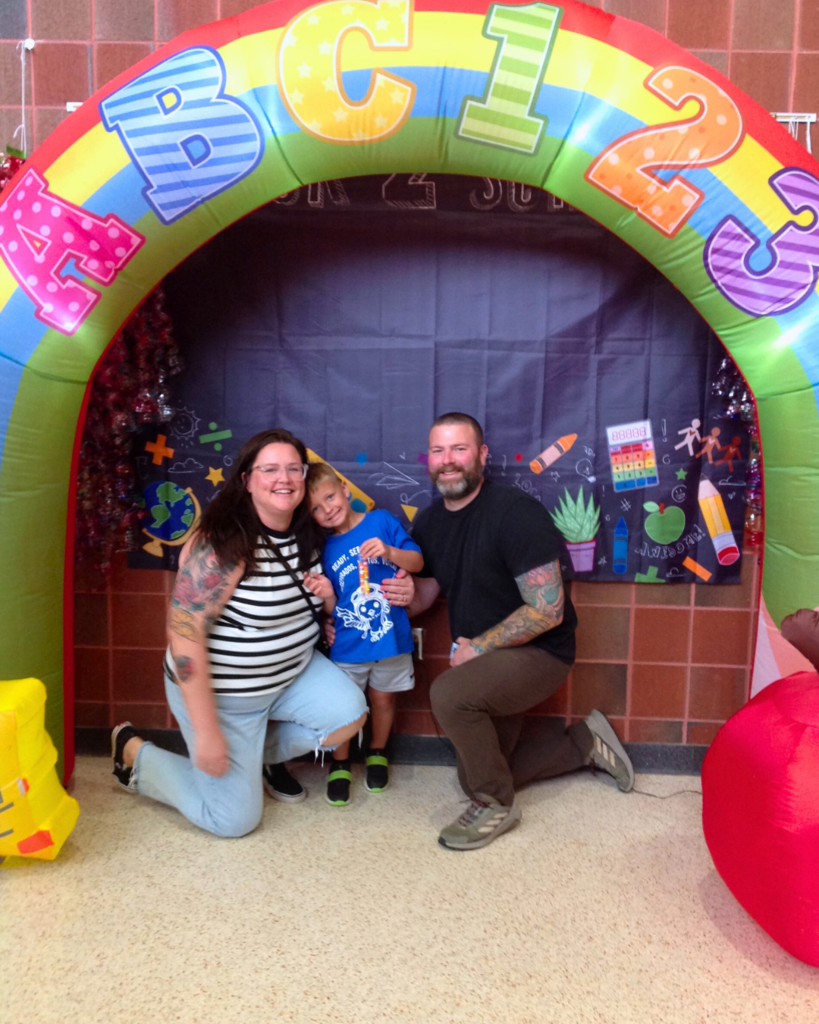 Young student and family pose for photo in front of backdrop for back to school.