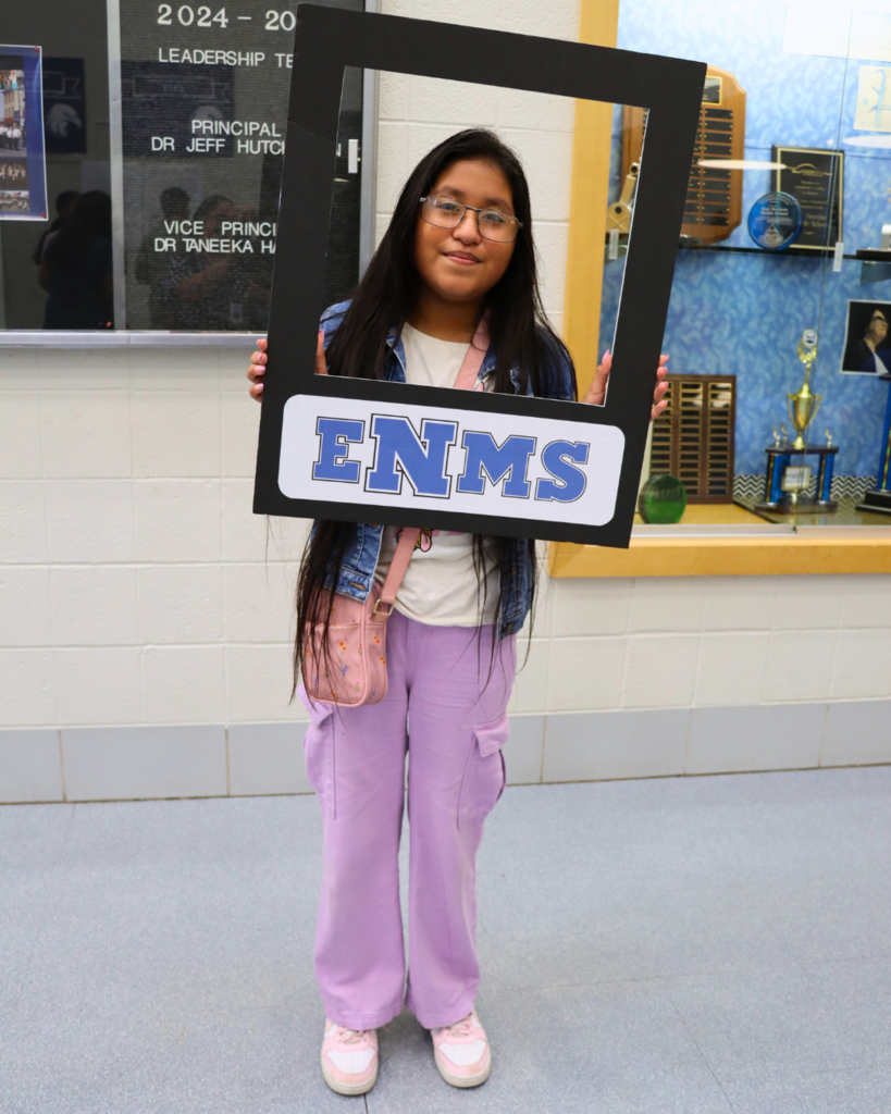 Student holding a poster photo frame smiles for a photo.