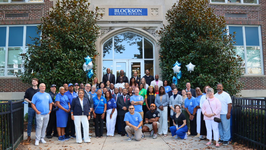 Large group of community partners standing on the steps of Blockson Middle School after welcome students.
