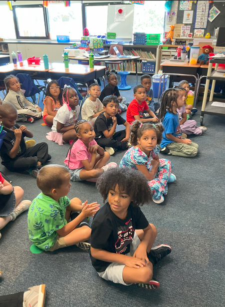 A group of students at the rug in their classroom.