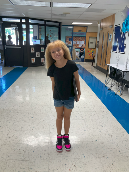 A student walking to class with their chromebook. 
