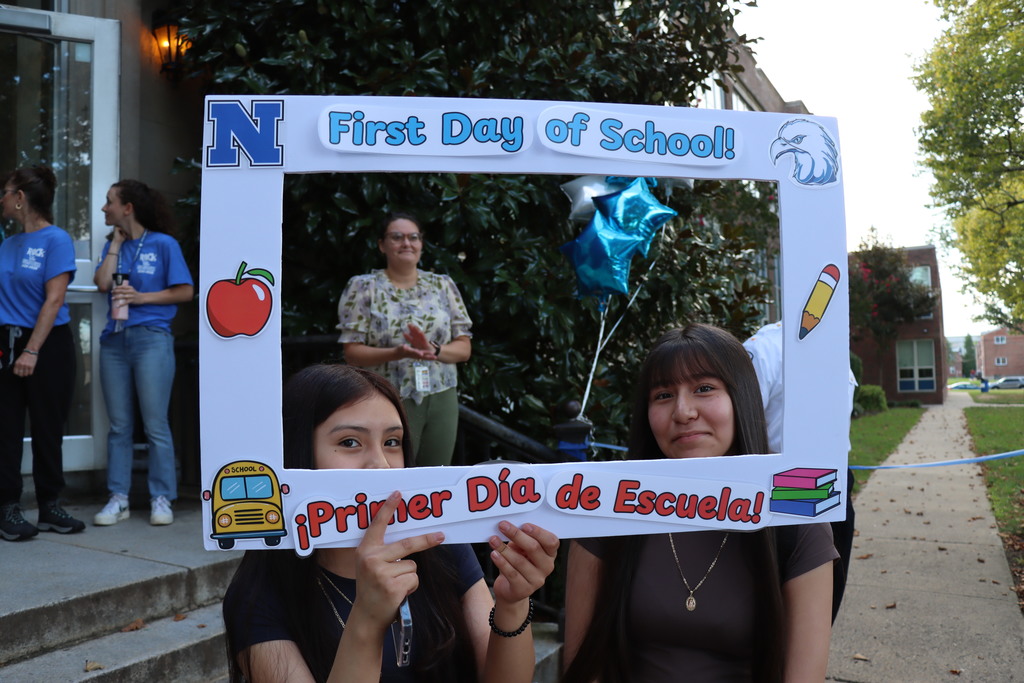 Two students in a photo booth square that says "First Day of School". More information in caption