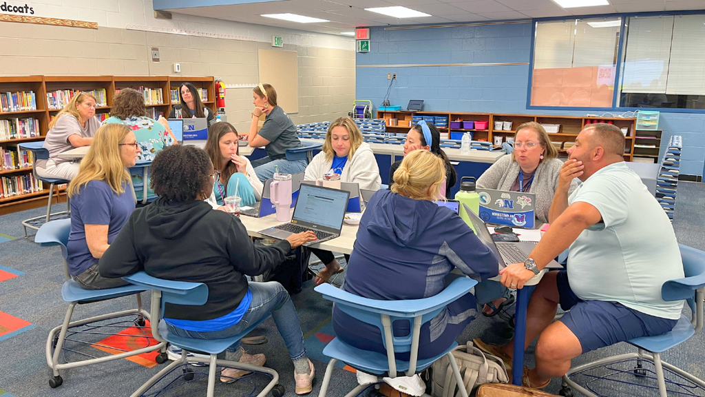 Group of teachers sit together at a table engaging in discussion. 