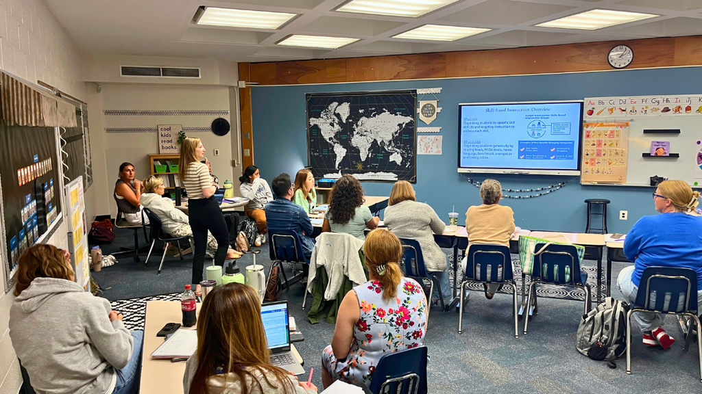 Presenter speaking in a classroom with teachers listening to presentation. 