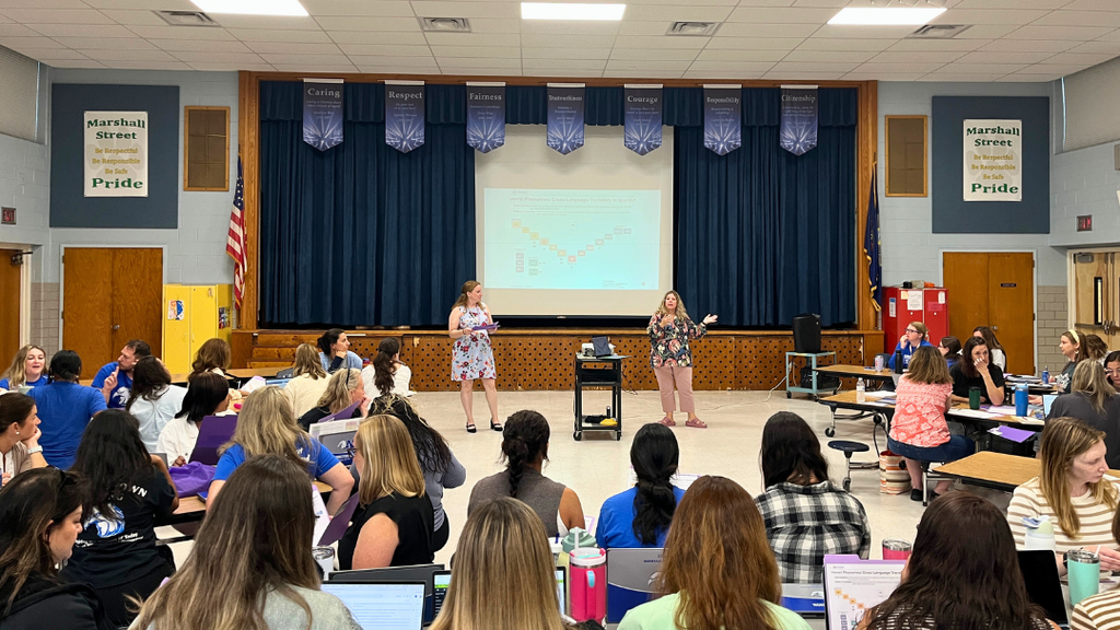 Two educators presenting in front of large group. 