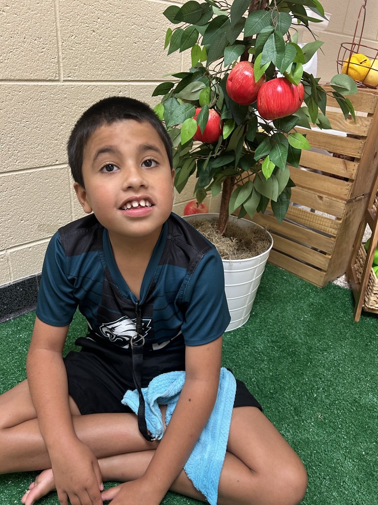 Photo of student sitting in front of an apple tree.