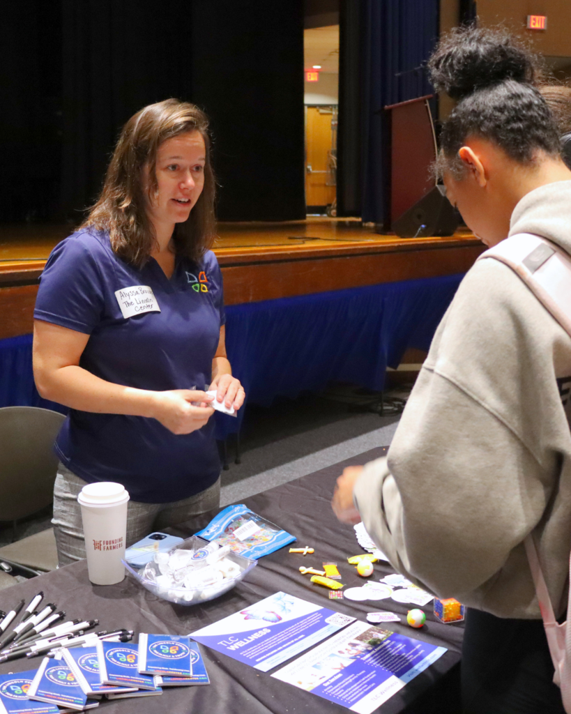 Community partner speaking to a student with items displayed on a table.