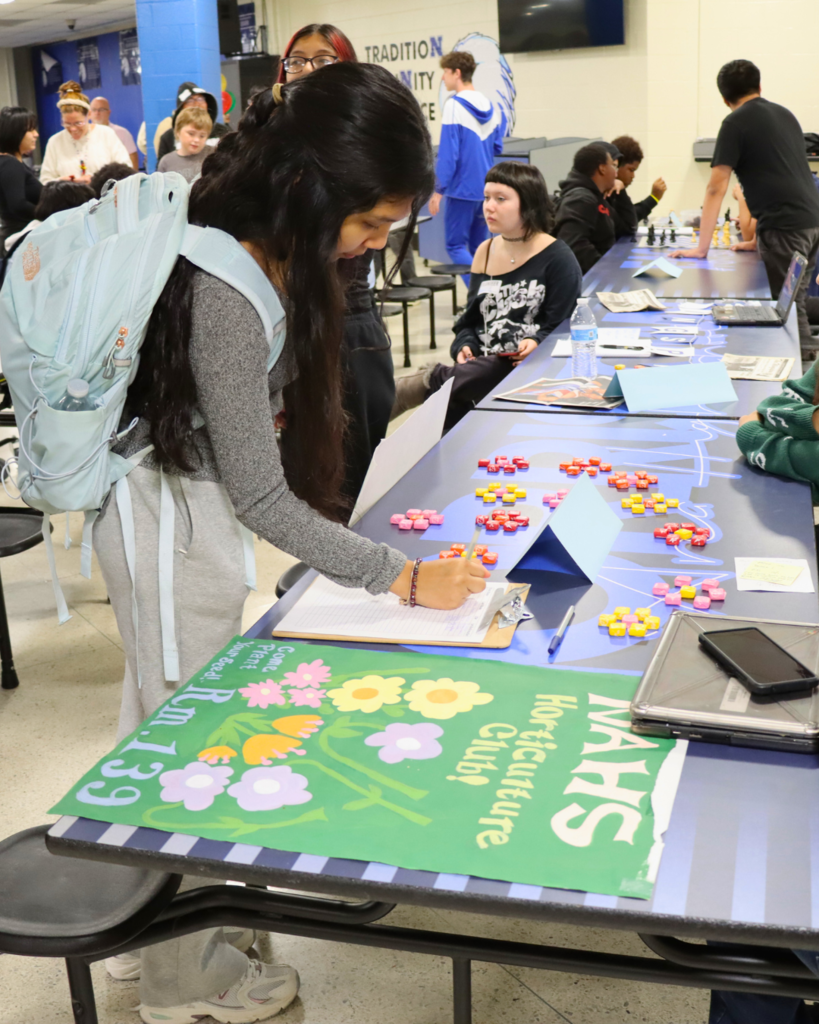 Student filling out signup sheet for NAHS horticulture club.