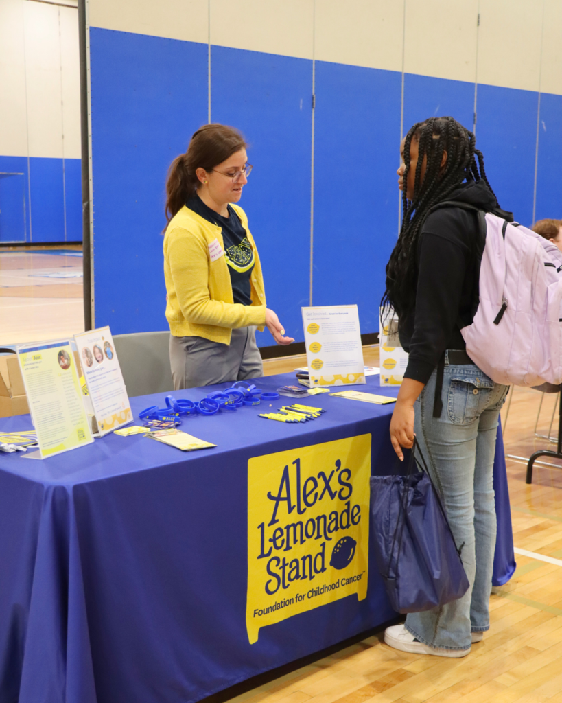Community partner speaking to a student with items displayed on a table.
