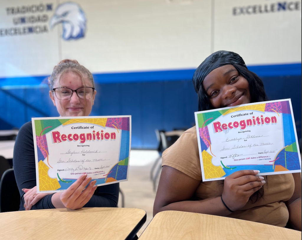 Two female students pose with their star student portraits.