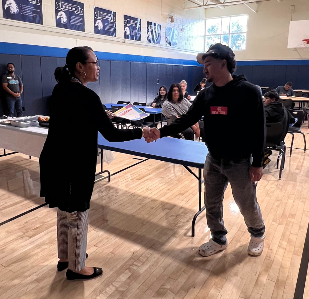 The principal is handing a certificate to a student who is being recognized as a star student. 