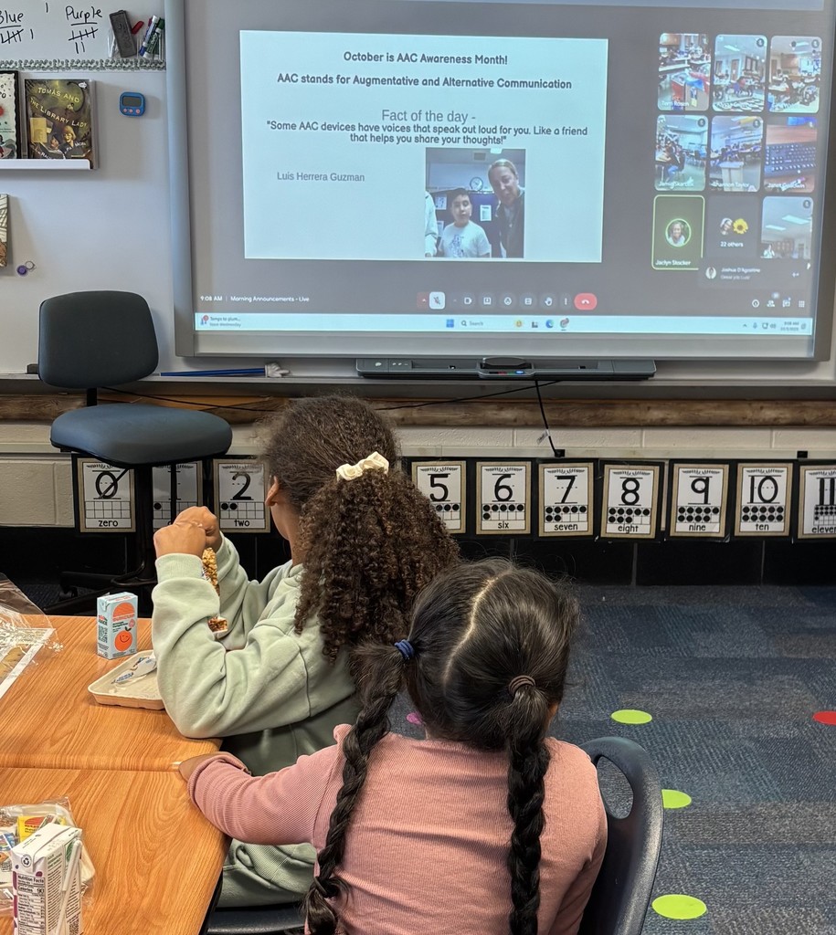 Photo of 2 students watching Luis and Mrs. Stocker delivering the morning announcements.