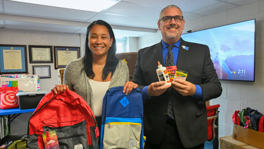 Jamila Winder and Chris Dormer pose for a photo holding donated school supplies.