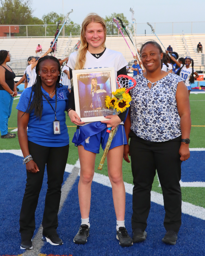 Student athlete and coaches pose for photo on turf field.