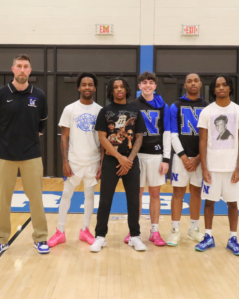 Senior Basketball players and coach pose for photo on the court.