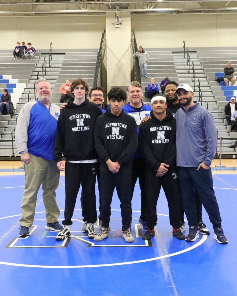 Wrestling team seniors standing with their coaches.